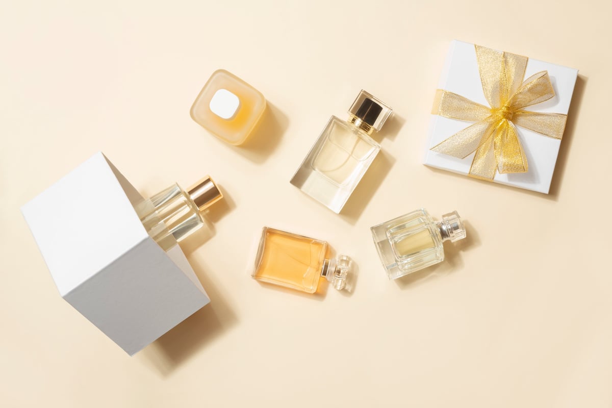 Perfume bottles and gift box flat lay on beige background